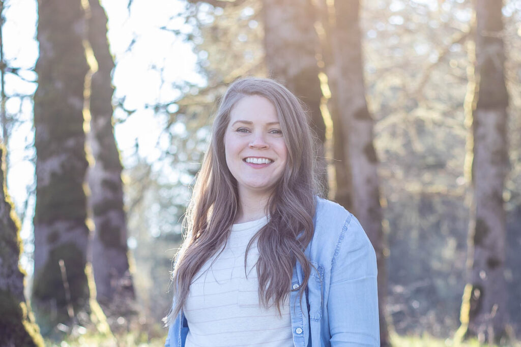 woman standing amongst trees.
