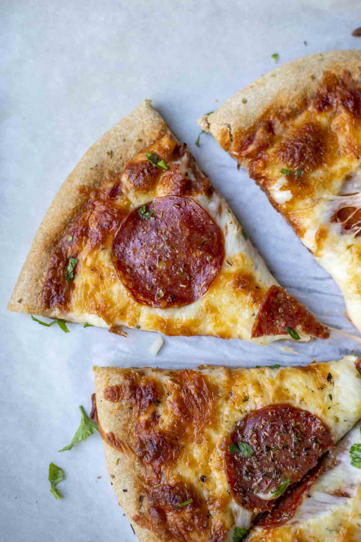 Slice of whole wheat pepperoni pizza separated from the rest of the pizza.