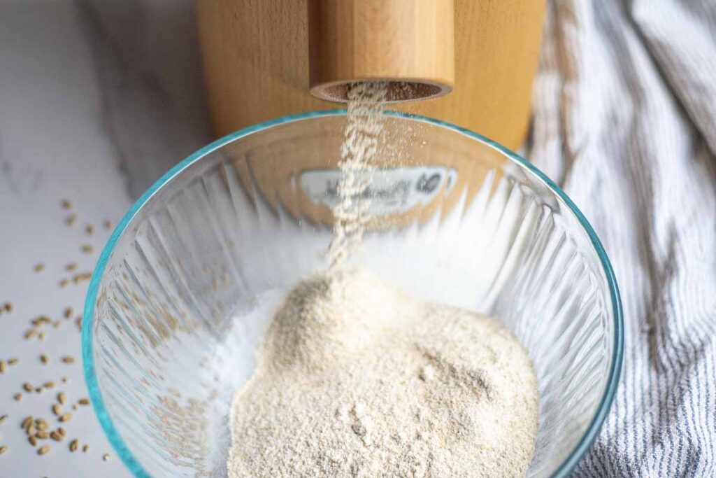 flour being milled into a glass bowl.