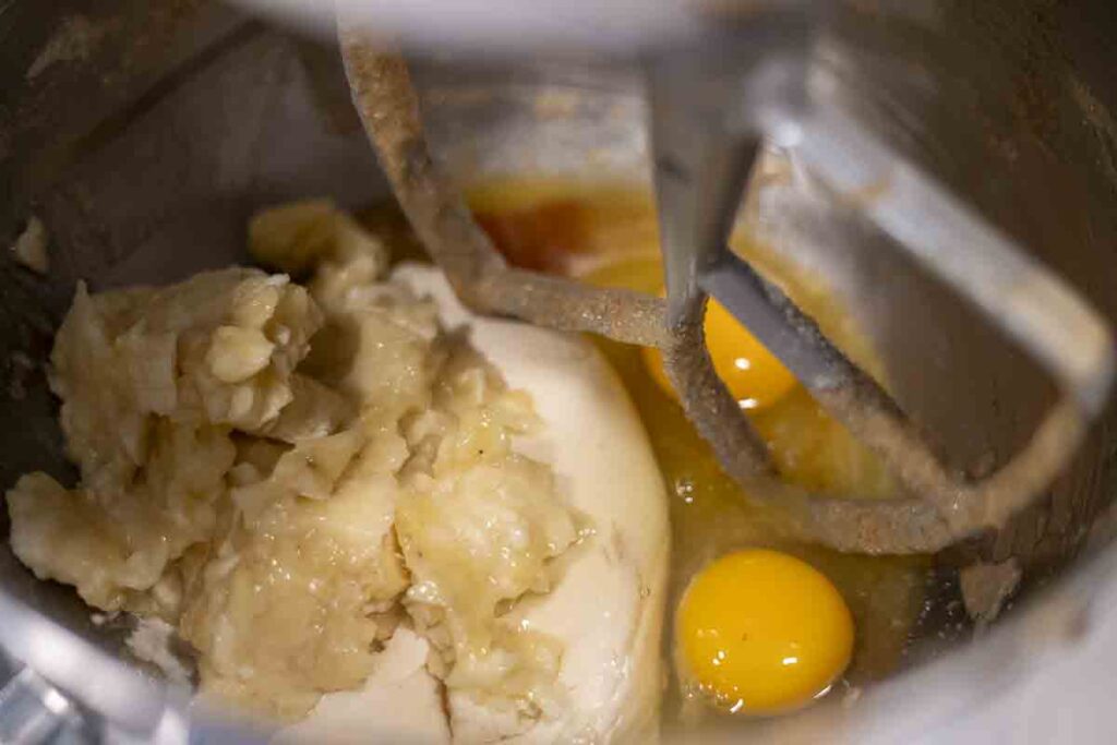 adding remaining wet ingredients into a stand mixer bowl with paddle attachment.